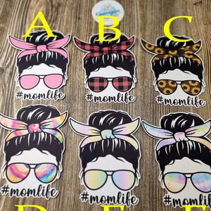 Peut inclure: Six designs diff&eacute;rents d'une femme avec un chignon d&eacute;sordonn&eacute;, des lunettes de soleil et un bandeau. Chaque design pr&eacute;sente un motif diff&eacute;rent sur le bandeau et les lunettes de soleil. Le texte '#momlife' est sous chaque design.