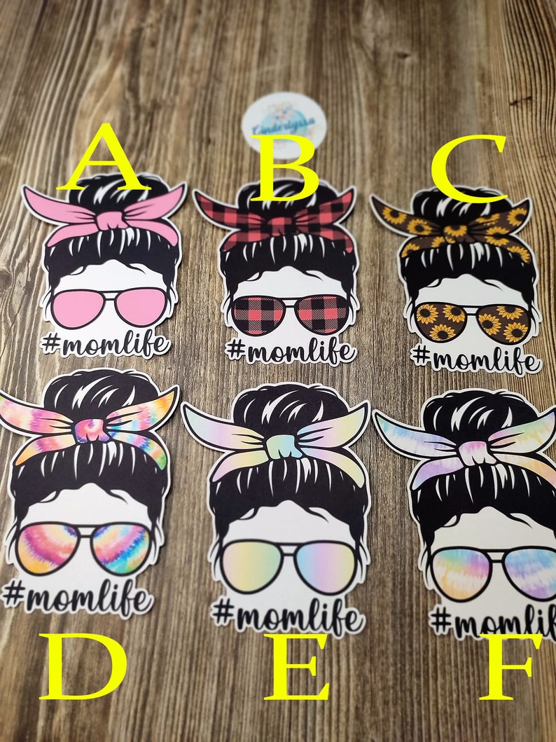 Peut inclure: Six designs diff&eacute;rents d'une femme avec un chignon d&eacute;sordonn&eacute;, des lunettes de soleil et un bandeau. Chaque design pr&eacute;sente un motif diff&eacute;rent sur le bandeau et les lunettes de soleil. Le texte '#momlife' est sous chaque design.