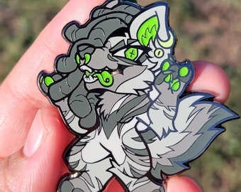 May include: A grey and white enamel pin of a cartoon wolf with green eyes and a green tongue. The wolf is standing on its hind legs with its front paws raised.
