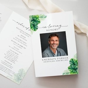 Op de afbeelding: Een wit programma voor een herdenkingsdienst met groene tropische bladeren en een foto van een man. Het programma bevat de volgorde van de dienst, een gebed, een favoriet lied, een lezing van de overlijdensadvertentie, een lofrede, dragers en informatie over de begrafenis. De tekst "In liefdevolle herinnering" staat bovenaan het programma in cursief.