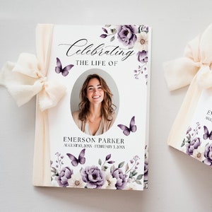 May include: A white memorial booklet with a floral design featuring purple and white flowers and butterflies. The booklet has a photo of a woman and the text "Celebrating the Life of Emerson Parker August 10, 20XX - February 3, 20XX".