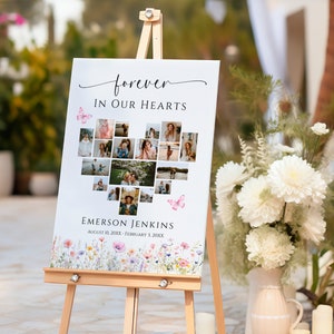 May include: A white canvas sign with a heart-shaped photo collage of a person surrounded by flowers. The sign reads "forever in our hearts" and "Emerson Jenkins" with dates.