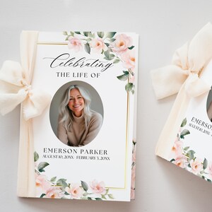 May include: Two memorial booklets with a floral design and a photo of a woman. The cover reads "Celebrating the Life of" and includes the name "Emerson Parker" and dates. The booklets are tied with a cream-colored ribbon.