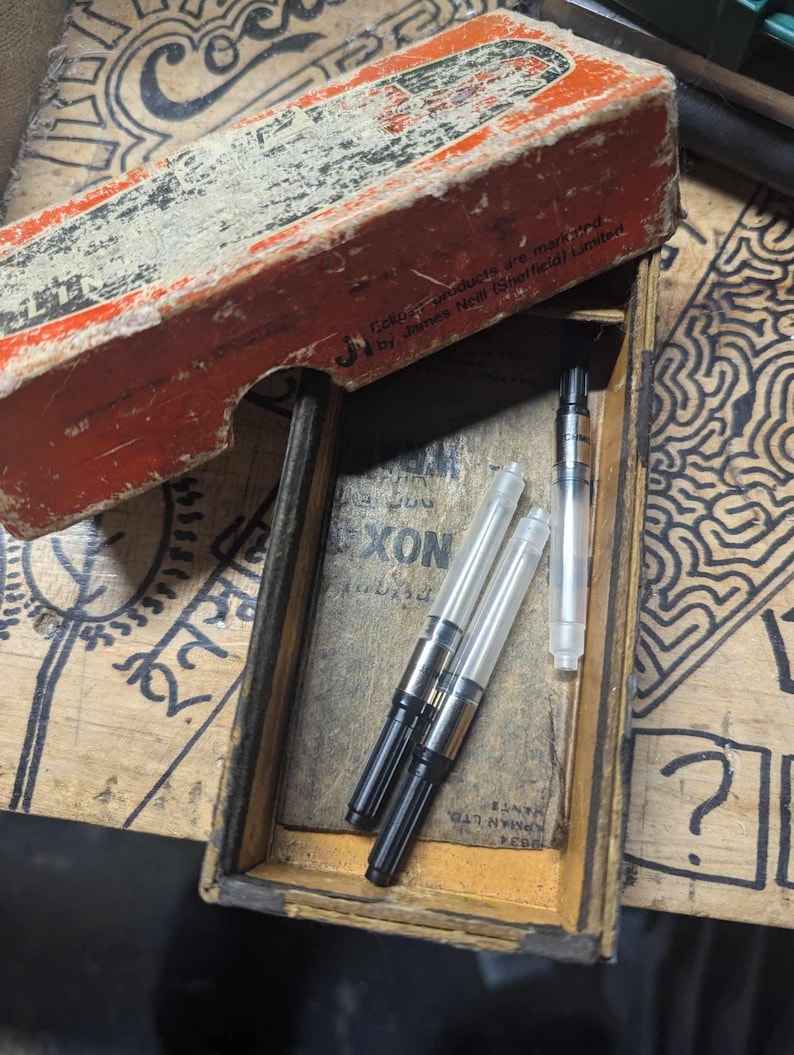 May include: A vintage wooden box, open to reveal pen nibs and ink cartridges. The box has a distressed red and white exterior. The text "Tekpar products are manufactured by James Neil (Sheffield) Limited" is printed on the box.