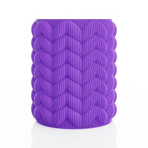 May include: A cylindrical, purple container with a textured, wave-like pattern. The design features vertical ridges that create a repeating chevron motif around the entire body of the container. The object is set against a white background.