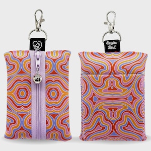May include: Two rectangular pouches featuring a wavy, psychedelic pattern in orange, pink, purple, and red. One pouch has a central vertical zipper with a silver bell charm and a black tag with a bird logo. The other has a black tag labeled Sweetie Bird.