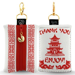 Pode incluir: Bolsa branca e vermelha com tema de comida chinesa para viagem, com zíper dourado e clipe dourado. A bolsa apresenta um zíper vermelho, um padrão vermelho e branco e as palavras "THANK YOU" e "ENJOY!" nas costas.
