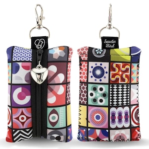 May include: Two colorful, patterned pouches with a silver clip and zipper. The pouches feature a geometric design in various colors, including red, blue, and yellow. One pouch has a heart-shaped charm on the zipper. The text "Sweetie Bird" is on one of the pouches.