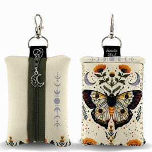 May include: Two small, rectangular pouches with keychains. One is cream-colored with a green zipper and a crescent moon charm. The other features a butterfly design with orange flowers and the text "Sweetie Bird". Both have a silver-colored keychain clip.