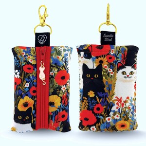 Puede incluir: Dos estuches con cremallera con un diseño floral y de gatos. Los estuches tienen una cremallera roja y un clip dorado. Un estuche tiene un gato negro y el otro un gato blanco. Los estuches están decorados con amapolas rojas, flores amarillas y flores azules.