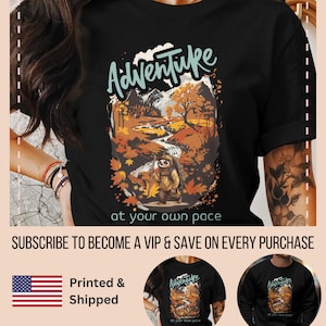 May include: Black t-shirt featuring a graphic of a sloth hiking in a forest with the text "Adventure at your own pace".