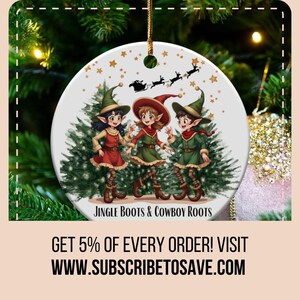 May include: A white round Christmas ornament with a festive design featuring three elves wearing green, red, and brown outfits, standing in front of a green Christmas tree. The ornament has the text "Jingle Boots & Cowboy Roots" at the bottom.