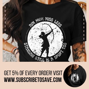 May include: Black t-shirt with a white circle graphic featuring a silhouette of an archer with a bow and arrow. The text "AIM HIGH MISS LESS STANDING STILL IS A SPORT TOO" is written around the circle.