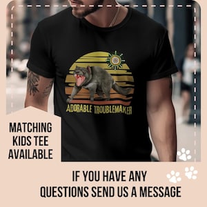 May include: A black t-shirt with a retro sunset graphic featuring a Tasmanian devil and the text "Adorable Troublemaker".