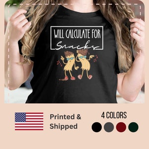 Könnte beinhalten: Schwarzes T-Shirt mit einem weißen Rechteck, auf dem "Will Calculate for Snacks" steht. Im Rechteck befinden sich zwei tanzende Cartoon-Nudeln mit Sonnenbrillen. Die Nudeln sind braun und gelb.