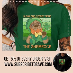 May include: Green t-shirt featuring a cartoon sloth wearing a leprechaun hat and holding a shamrock. The text "Slow and steady wins" and "The Shamrock" are printed on the shirt.