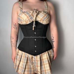 May include: A black corset with a plaid skirt. The corset has a lace-up front and is made of a sturdy fabric. The skirt is a mini-length and has a pleated design.