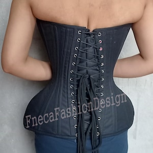 May include: Black corset with a lace-up back and metal eyelets. The corset has a smooth, satin-like finish and is cinched at the waist. The text "FnecaFashionDesign" is printed on the front of the corset.