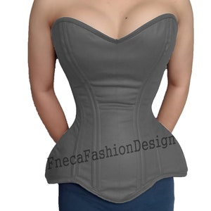 May include: A gray strapless corset with a sweetheart neckline and a pointed bottom. The corset has boning and is made of a smooth fabric. The text "FnecaFashionDesign" is printed on the front of the corset.