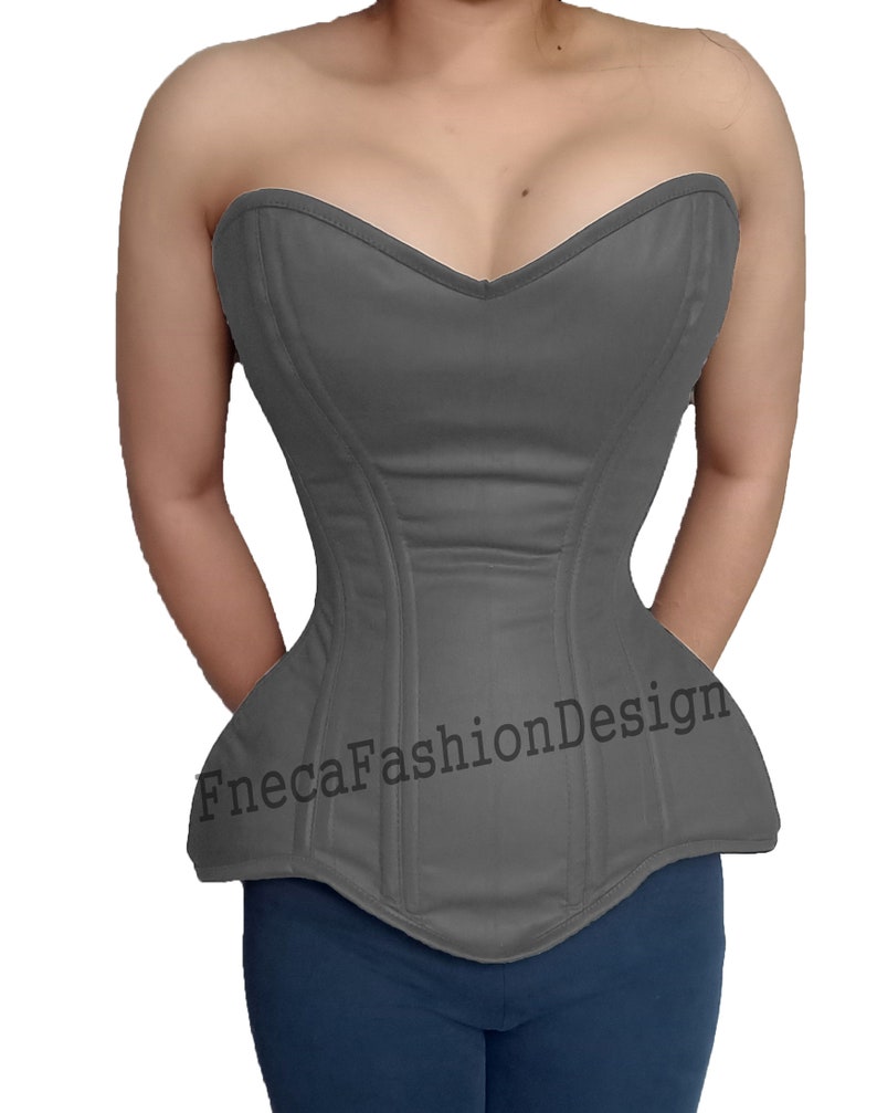 May include: A gray strapless corset with a sweetheart neckline and a pointed bottom. The corset has boning and is made of a smooth fabric. The text "FnecaFashionDesign" is printed on the front of the corset.