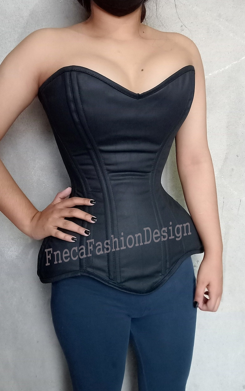 May include: A black strapless corset with boning and a sweetheart neckline. The corset has a smooth, satin-like finish and a pointed bottom.