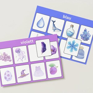 Puede incluir: Dos tarjetas con ilustraciones en acuarela. Una tarjeta está etiquetada como "blau" y presenta imágenes de una gota de agua, una ballena, una botella y cristales. La otra tarjeta está etiquetada como "violett" y muestra imágenes de uvas, una medusa, una pluma y una flor.