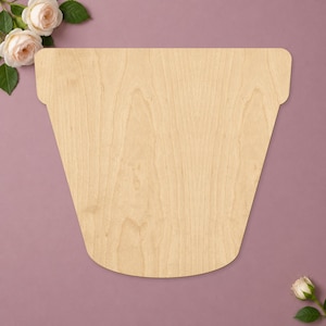 May include: A flat, light-colored wooden cutout shaped like a flower pot with a wide rim and tapered sides. The wood grain is visible across the surface, and the object is positioned against a solid, muted purple background.