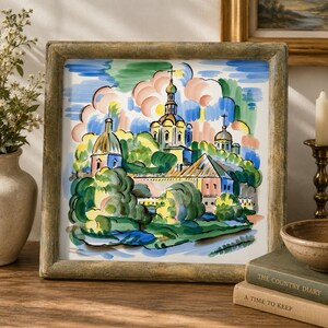 May include: A square framed painting featuring a colorful, expressive landscape with stylized buildings, golden domes, and crosses. The artwork uses bold brushstrokes in shades of green, blue, pink, and yellow to depict a church complex surrounded by trees.