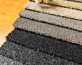 May include: A fabric swatch book with a variety of gray and black fabric samples. The swatches are arranged in a gradient from light gray to black.
