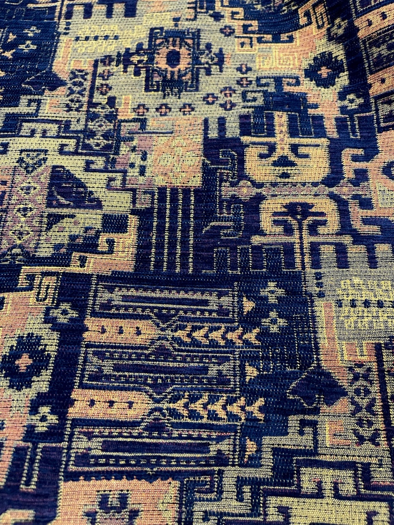 May include: A close-up of a fabric with a geometric pattern in shades of blue, yellow, and orange. The fabric has a textured surface and a woven appearance.