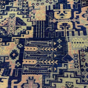 May include: A close-up of a fabric with a geometric pattern in shades of blue, yellow, and pink. The fabric has a textured surface and a woven appearance.