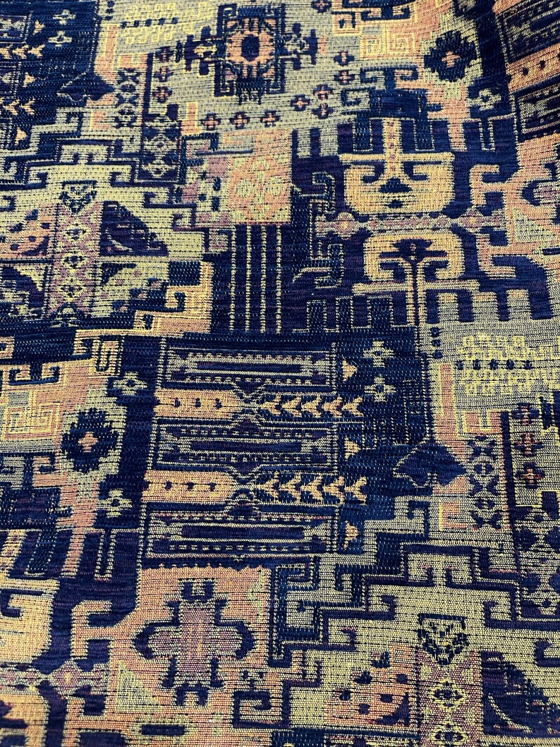 May include: A close-up of a fabric with a geometric pattern in shades of blue, yellow, and pink. The fabric has a textured surface and a woven appearance.