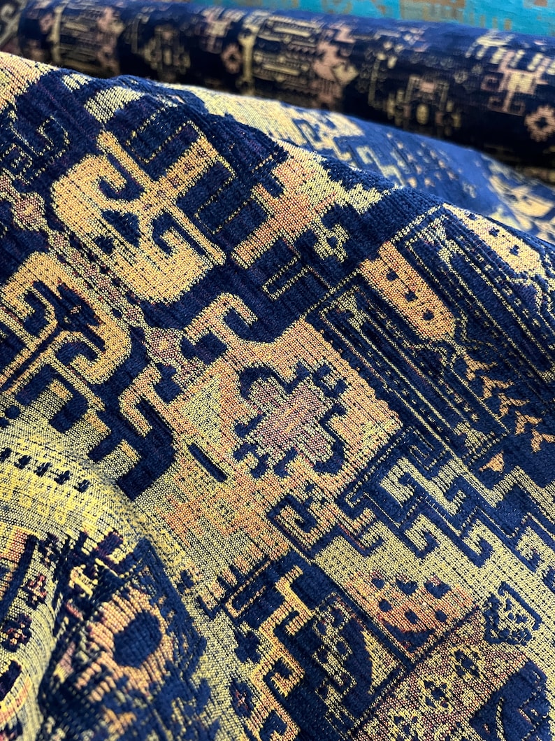 May include: Close-up of a blue and yellow patterned fabric with a textured surface. The fabric has a geometric design with repeating patterns.