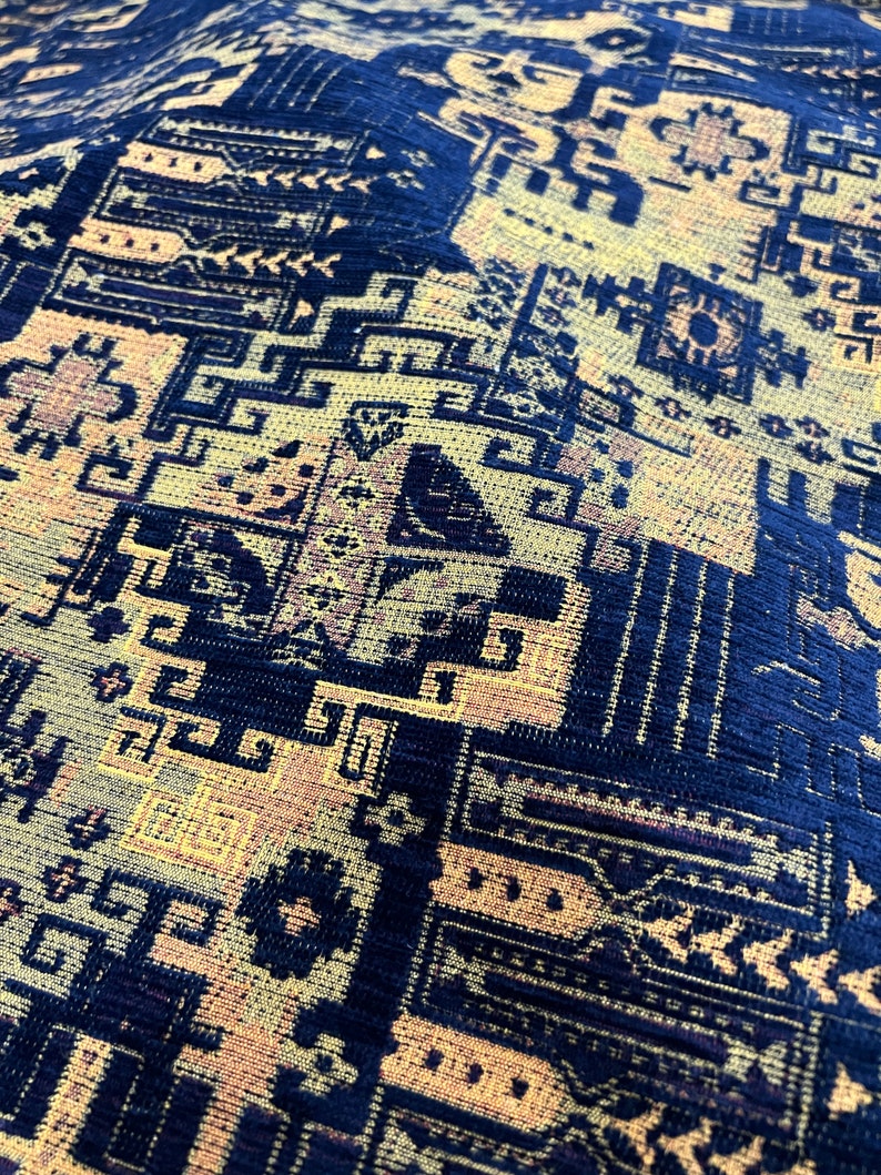 May include: Close-up of a blue and gold patterned fabric with a geometric design. The fabric has a textured surface and a woven appearance.