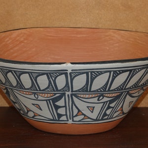Puede incluir: Un cuenco de terracota con un diseño geométrico en blanco y negro. El cuenco tiene un borde ancho y una base acampanada.