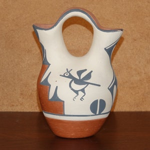 Può includere: Un'anfora in ceramica bianca di stile nativo americano con base marrone e un disegno di uccello nero e blu.
