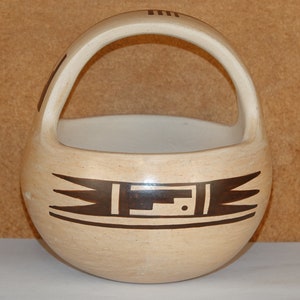 May include: A tan ceramic bowl with a brown geometric design and a handle. The bowl is a traditional Native American style.