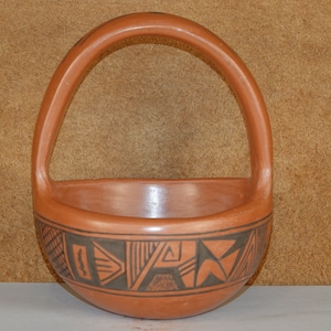 May include: A hand-crafted terracotta pottery basket with a handle. The basket is decorated with black geometric designs.