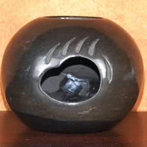 Op de afbeelding: Zwarte keramische pot met een berenpootontwerp. De pot heeft een ronde vorm en een brede opening.