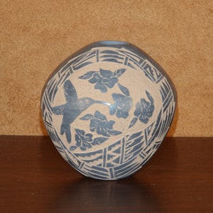 May include: A blue and white ceramic pot with a hummingbird and flowers design. The pot is decorated with a geometric pattern.