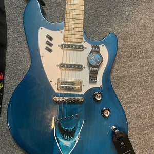 May include: A blue electric guitar with a white pickguard and a shark tooth sticker. The guitar has a wooden neck and a silver watch attached to the headstock.