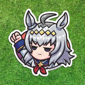 May include: A sticker featuring a cartoon character with silver hair, a stern expression, and a raised fist. The character wears a blue and red outfit with a red bow. The sticker is on a green background, and the text "ARTOFRDICKS.COM" is visible.