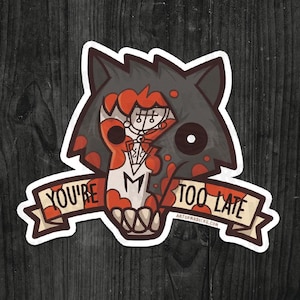 May include: A sticker featuring a stylized wolf head with a grey and red colour scheme. The wolf's face has a skull-like appearance with a white and red design. A banner below reads "YOU'RE TOO LATE."