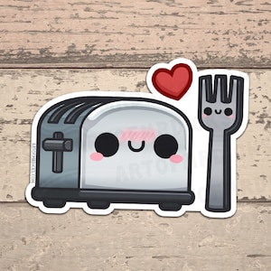 Könnte beinhalten: Ein Aufkleber mit einem Cartoon-Toaster mit einem lächelnden Gesicht, Rouge und einem roten Herzen darüber. Neben dem Toaster befindet sich eine lächelnde Gabel. Der Aufkleber hat einen weißen Rand und befindet sich auf einem Holzgrund.