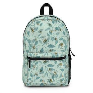 May include: A light blue backpack with a pattern of bees and leaves. The bees are yellow and black, and the leaves are green. The backpack has a black zipper and a black mesh pocket on the side.