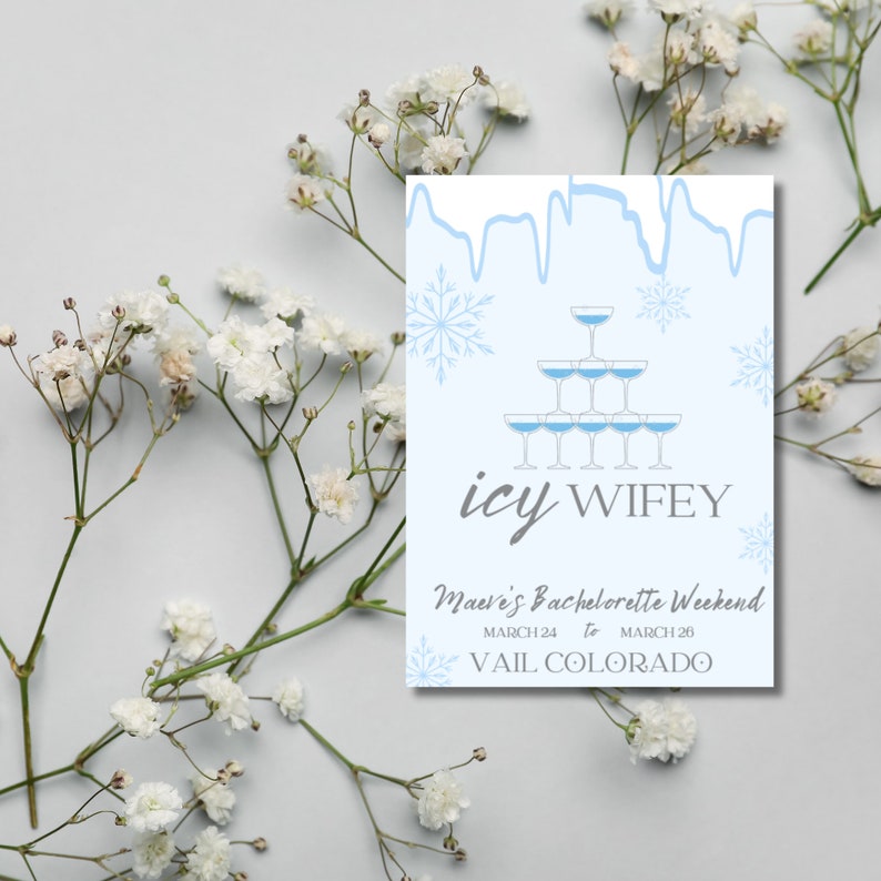Op de afbeelding: Een blauwe en witte uitnodigingskaart met een afbeelding van een champagne-glaspiramide en sneeuwvlokken. De tekst luidt "icy wifey" en "Maeve's Bachelorette Weekend, March 24 to March 26, Vail Colorado."
