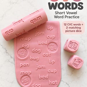 May include: A pink rolling pin and a flat pink mat, both embossed with CVC words and icons, alongside two pink dice featuring illustrations. The text reads CVC WORDS Short Vowel Word Practice, 12 CVC words + 2 matching picture dice, and PRIMLEY STUDIOS.