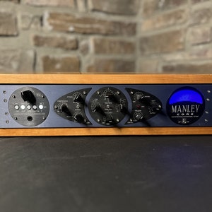 May include: A Manley CORE Reference Channel Strip in a wooden case. The front panel features a blue VU meter with the text "MANLEY CORE REFERENCE CHANNEL STRIP" and a series of knobs and switches.