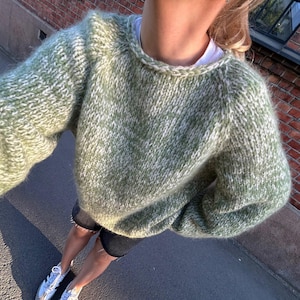 Peut inclure: Un pull en maille bouclée vert et blanc avec un col rond.