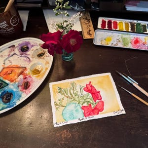 Puede incluir: Acuarela de flores rojas y vegetación en un jarrón turquesa, con el texto "Roses & Privet" y "April 17, 2024". La pintura está sobre papel blanco con fondo amarillo. Se ven pinceles y una paleta.